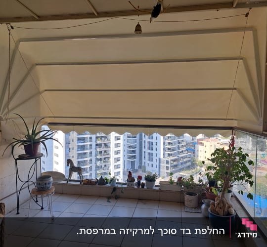 סוכך בד לבן תלוי מעל מרפסת עם צמחים